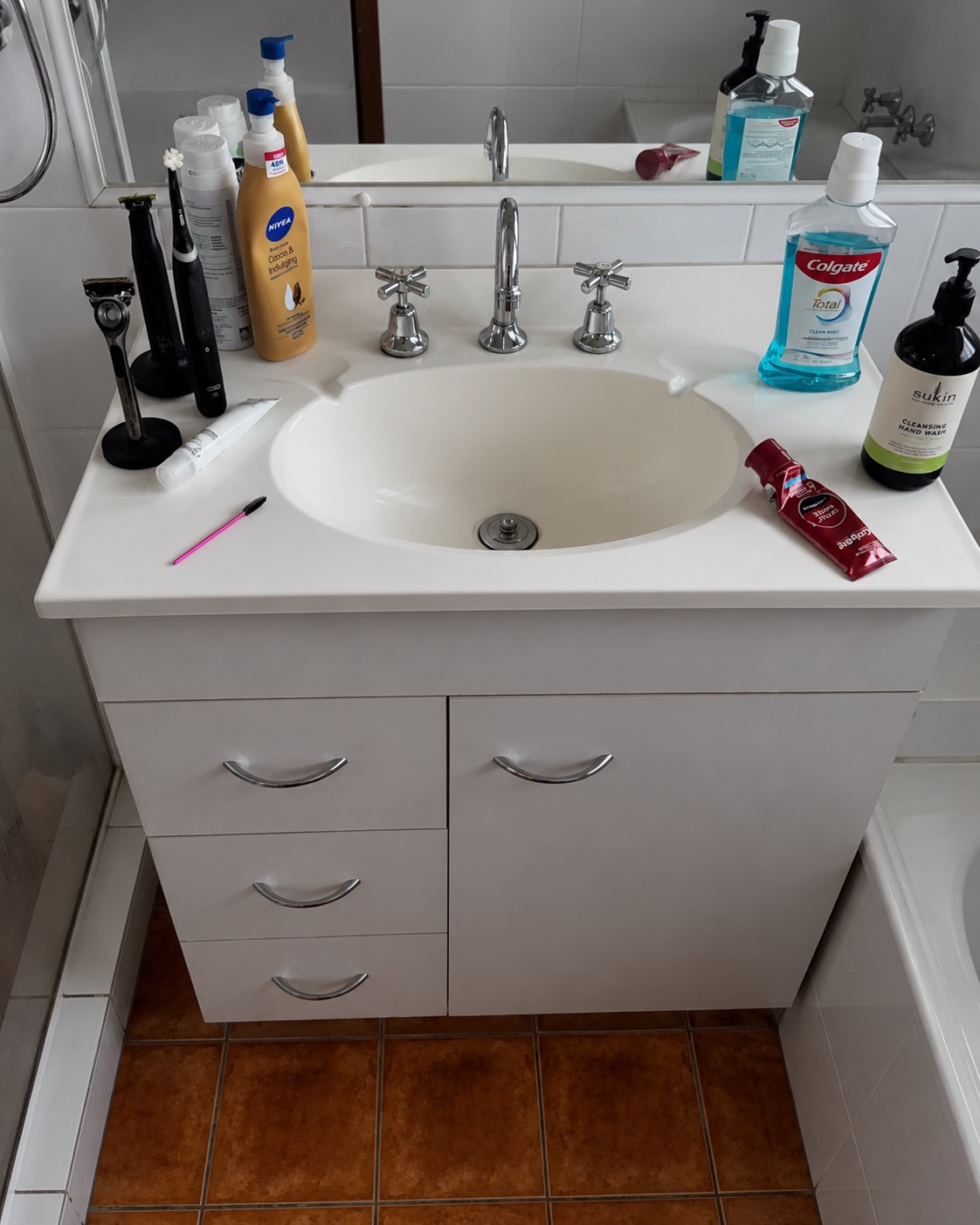 Cluttered white bathroom vanity before Lumi Cleaning